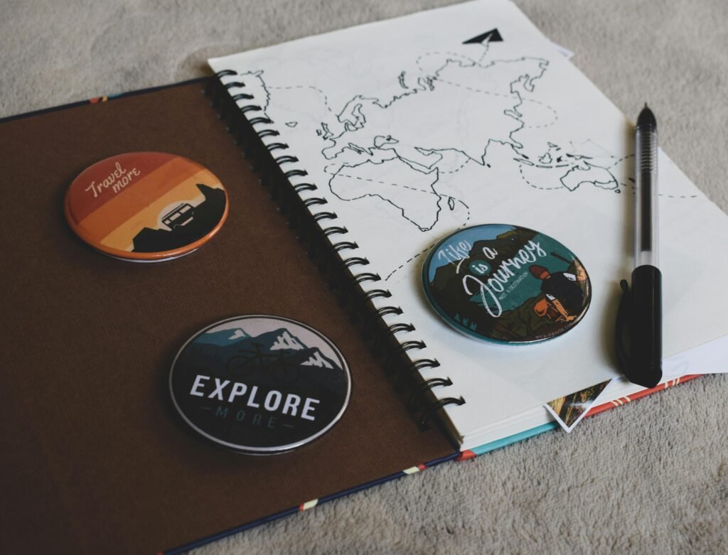 Flat lay of travel-themed accessories including a map, journal, and pins promoting exploration.